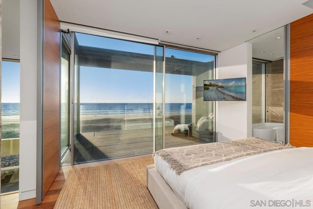 bedroom featuring light hardwood / wood-style floors, multiple windows, expansive windows, and a water view