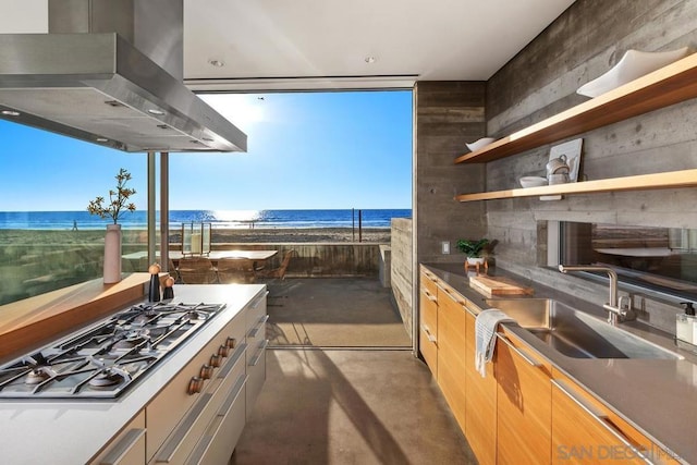 view of patio with a water view, a view of the beach, and sink