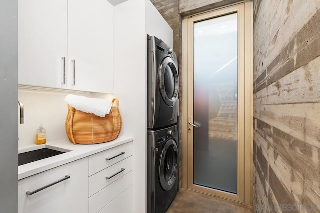 laundry area with sink, cabinets, and stacked washer and clothes dryer