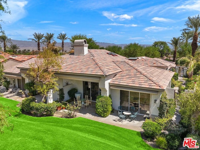 back of property featuring a mountain view, a yard, and a patio