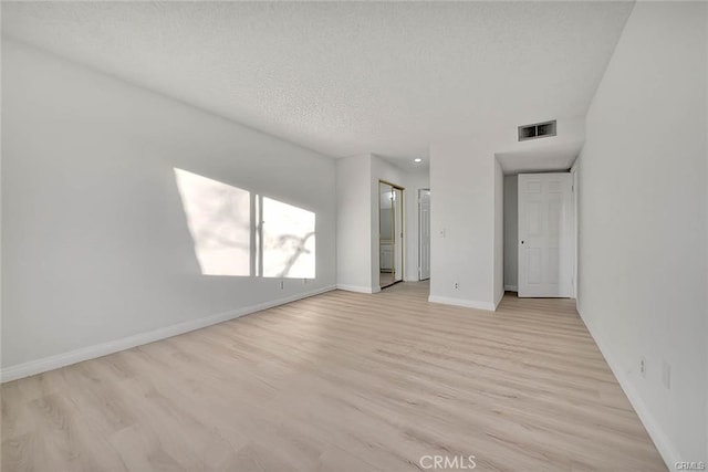 spare room featuring a textured ceiling and light wood-type flooring