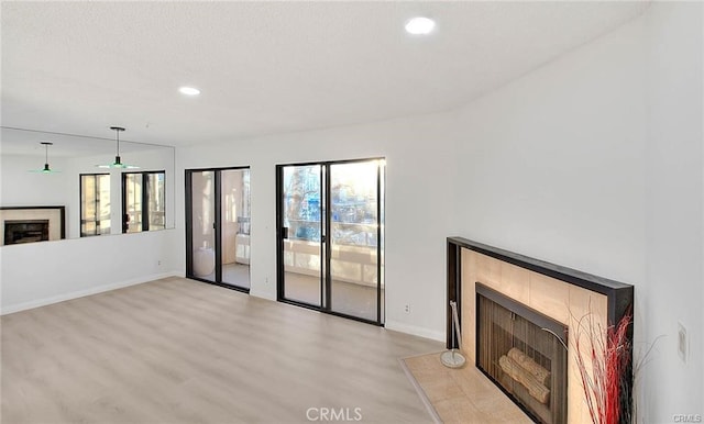 unfurnished living room with plenty of natural light, light hardwood / wood-style floors, french doors, and a tile fireplace