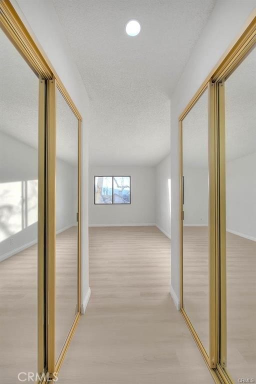 hall featuring a textured ceiling and light wood-type flooring