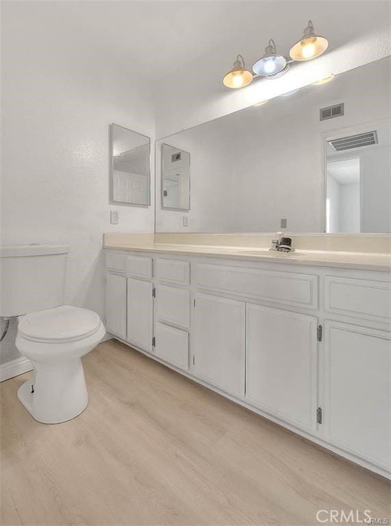 bathroom featuring toilet, hardwood / wood-style floors, and vanity