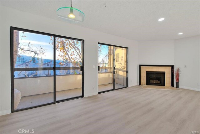 460 Oak St Unit 201, Glendale, CA 91204 - unfurnished living room featuring wood finished floors, baseboards, recessed lighting, a tile fireplace, and a textured ceiling