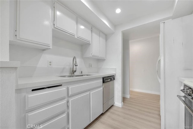 kitchen featuring dishwasher, sink, white refrigerator, white cabinetry, and light hardwood / wood-style floors