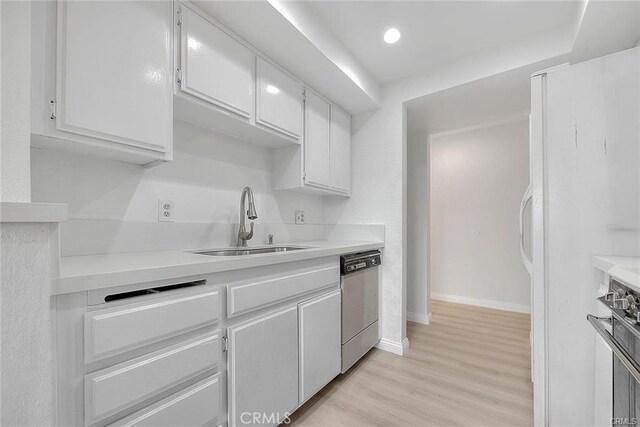 460 Oak St Unit 201, Glendale, CA 91204 - kitchen with stainless steel appliances, a sink, white cabinets, light wood finished floors, and baseboards