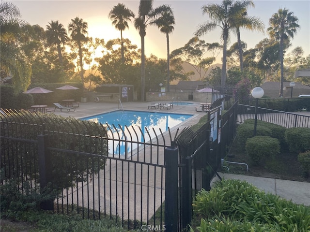 pool at dusk featuring a patio