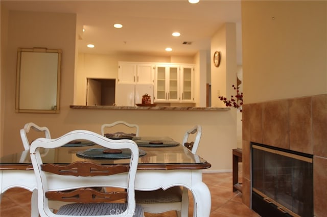 dining room featuring light tile patterned floors and a tiled fireplace