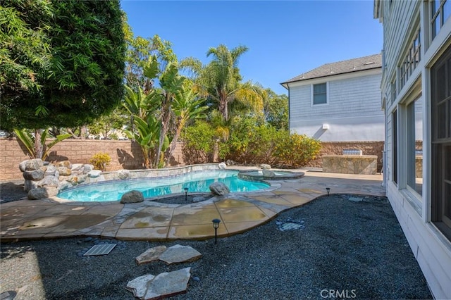 view of pool with a pool with connected hot tub, a fenced backyard, and a patio