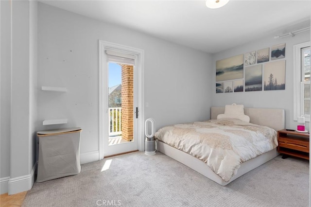 carpeted bedroom featuring access to outside, multiple windows, and baseboards