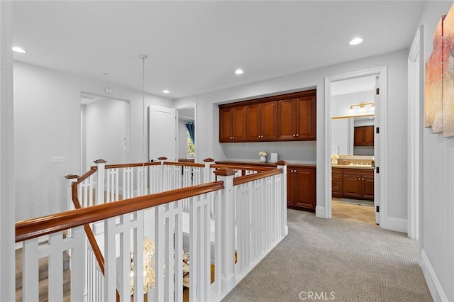 hallway featuring baseboards, recessed lighting, an upstairs landing, and light colored carpet