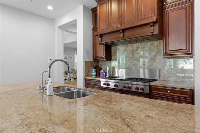 kitchen with custom range hood, light stone counters, a sink, stainless steel gas stovetop, and backsplash