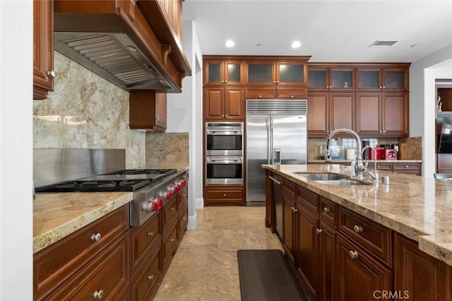 kitchen with stainless steel appliances, visible vents, a sink, wall chimney range hood, and light stone countertops