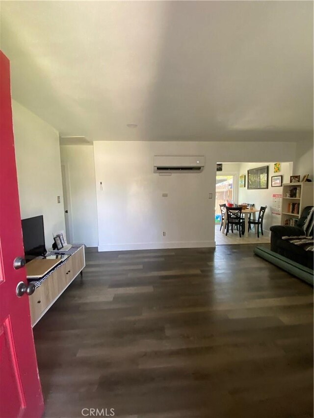 living room featuring a wall mounted air conditioner and dark hardwood / wood-style flooring