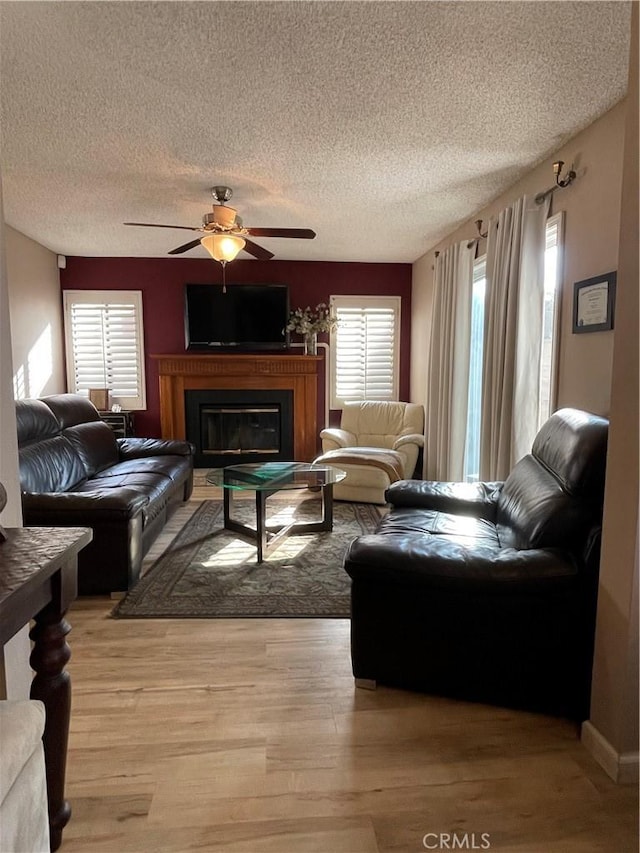 living room featuring light hardwood / wood-style floors, a textured ceiling, and ceiling fan