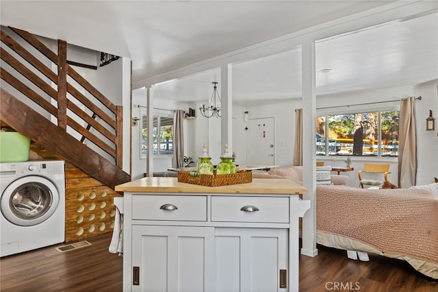 laundry room with washer / dryer, dark wood-type flooring, crown molding, cabinets, and a chandelier