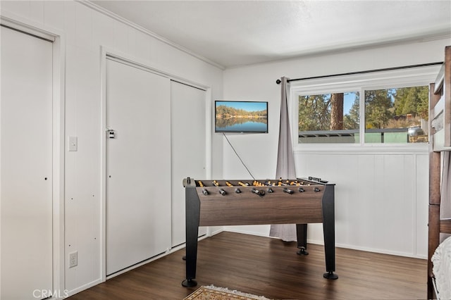 recreation room featuring dark wood-type flooring and crown molding