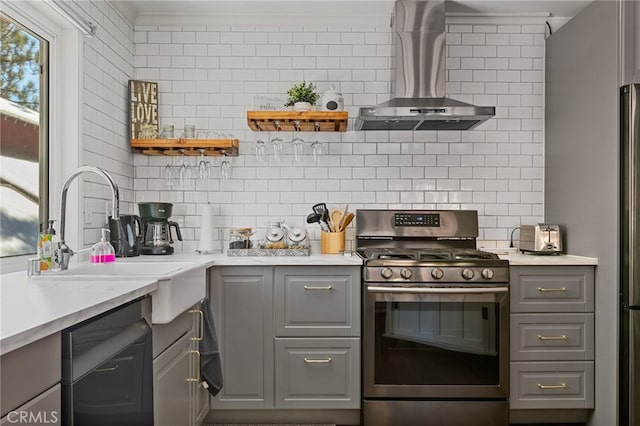 kitchen with gas range, decorative backsplash, gray cabinets, and wall chimney range hood