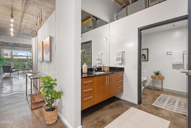 bathroom featuring toilet, vanity, a towering ceiling, and concrete flooring