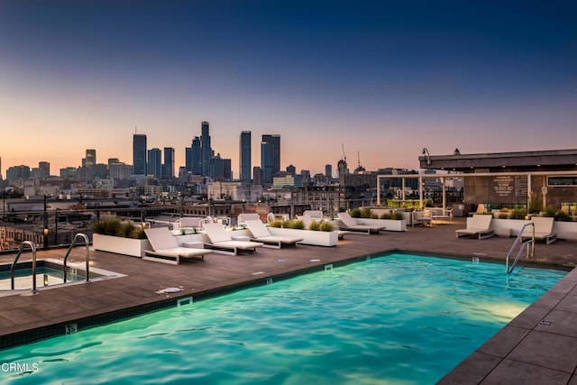 pool at dusk featuring a hot tub