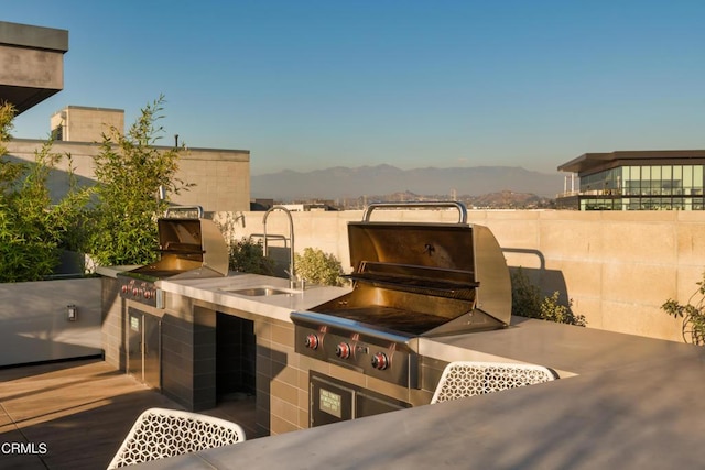 view of patio featuring grilling area, a mountain view, exterior kitchen, and sink