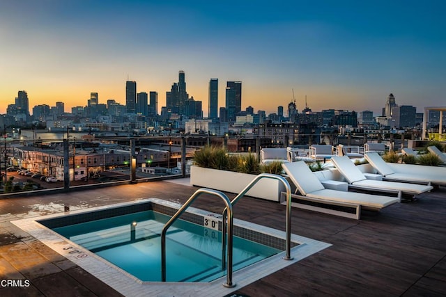 pool at dusk with a hot tub