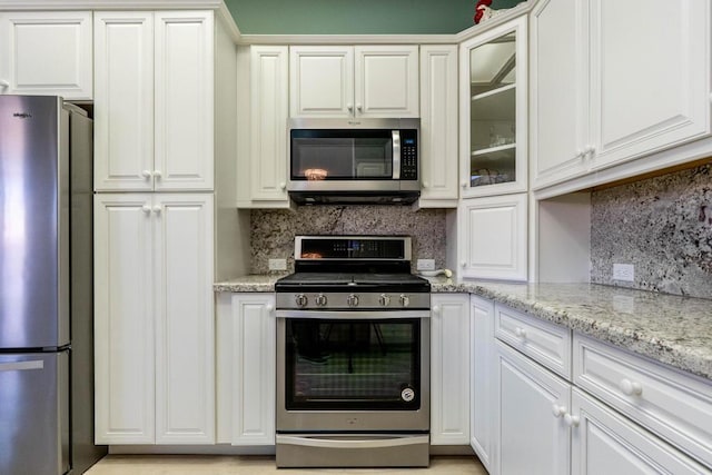 kitchen featuring backsplash, stainless steel appliances, white cabinets, and light stone counters