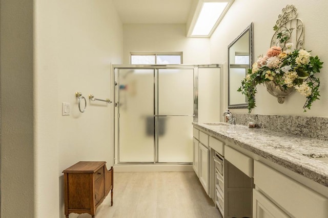 bathroom featuring hardwood / wood-style floors, a shower with door, and vanity