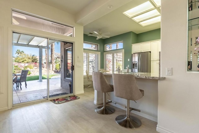 kitchen featuring white cabinets, a breakfast bar area, stainless steel refrigerator with ice dispenser, and plenty of natural light