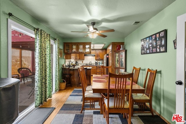 dining room with ceiling fan, sink, a textured ceiling, and light wood-type flooring