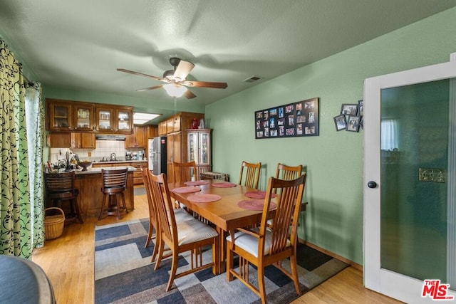 dining area with ceiling fan, light hardwood / wood-style flooring, and sink