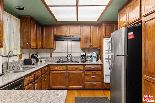 kitchen with decorative backsplash, sink, light hardwood / wood-style floors, and appliances with stainless steel finishes