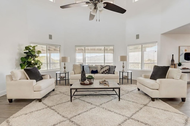 living room featuring ceiling fan, a high ceiling, and plenty of natural light