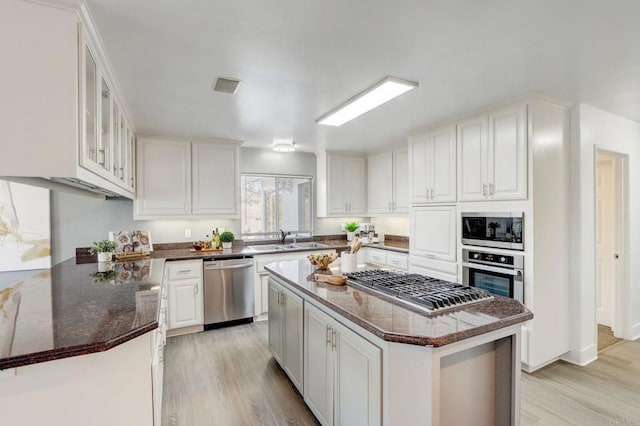 kitchen featuring white cabinets, a center island, dark stone counters, and appliances with stainless steel finishes