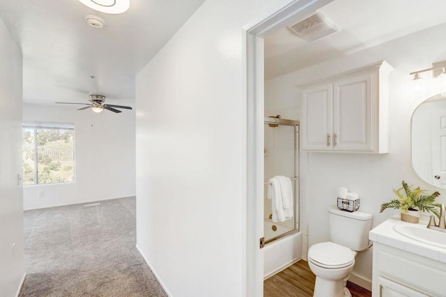 full bathroom featuring toilet, ceiling fan, combined bath / shower with glass door, and vanity