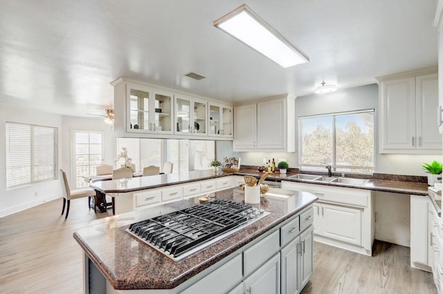 kitchen with a kitchen island, white cabinetry, sink, ceiling fan, and stainless steel gas stovetop