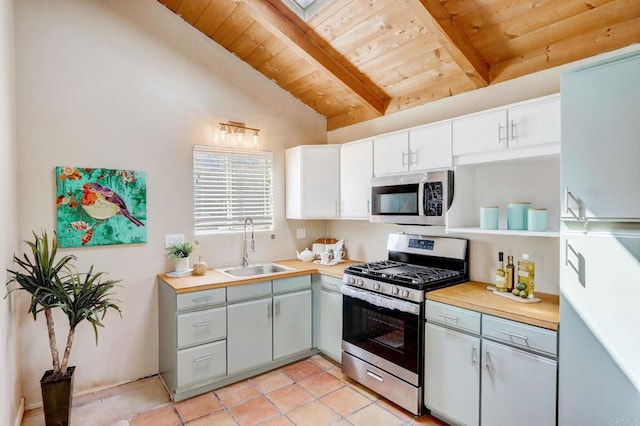 kitchen with white cabinets, stainless steel appliances, vaulted ceiling with beams, sink, and wooden ceiling