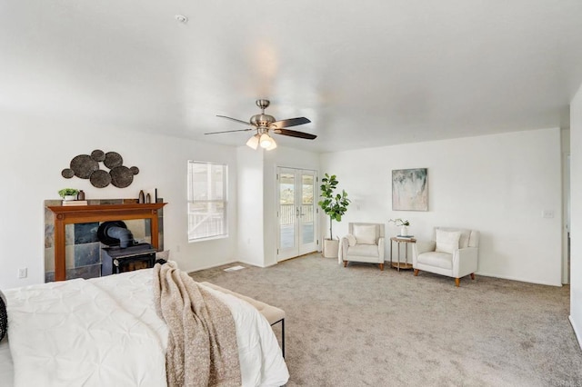 bedroom with ceiling fan, french doors, carpet, and a wood stove