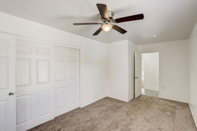 unfurnished bedroom with ceiling fan, light colored carpet, and a closet