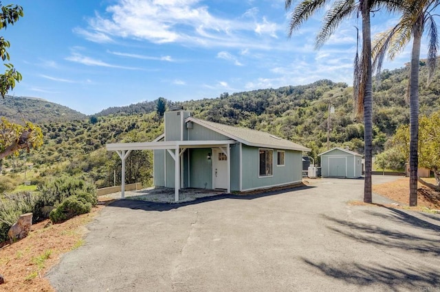 view of front of property featuring a mountain view and a storage shed