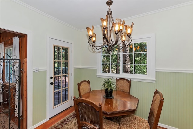 dining area with ornamental molding, an inviting chandelier, and hardwood / wood-style floors