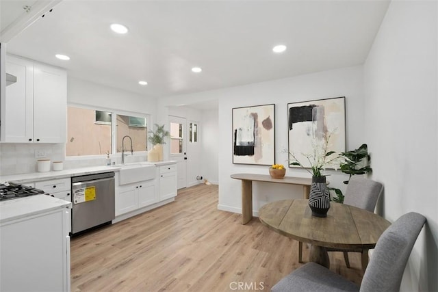 kitchen with white cabinets, light hardwood / wood-style floors, stainless steel dishwasher, and sink