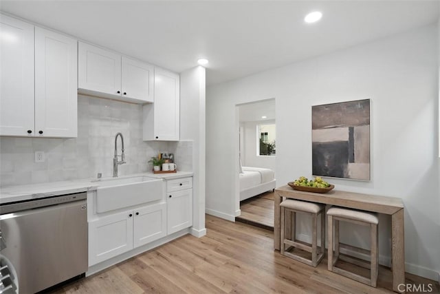 kitchen featuring backsplash, sink, stainless steel dishwasher, light hardwood / wood-style floors, and white cabinetry