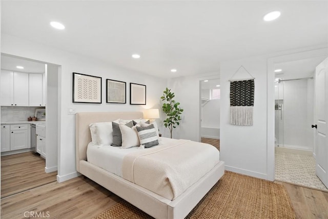 bedroom featuring connected bathroom, light hardwood / wood-style flooring, and a spacious closet