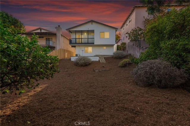 back house at dusk featuring a balcony