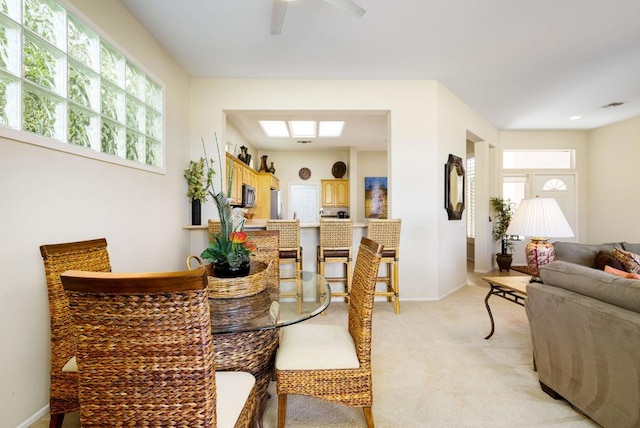 dining space with a skylight and light carpet