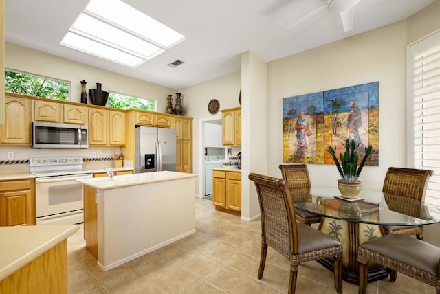 kitchen featuring a center island with sink, plenty of natural light, washer / clothes dryer, and appliances with stainless steel finishes