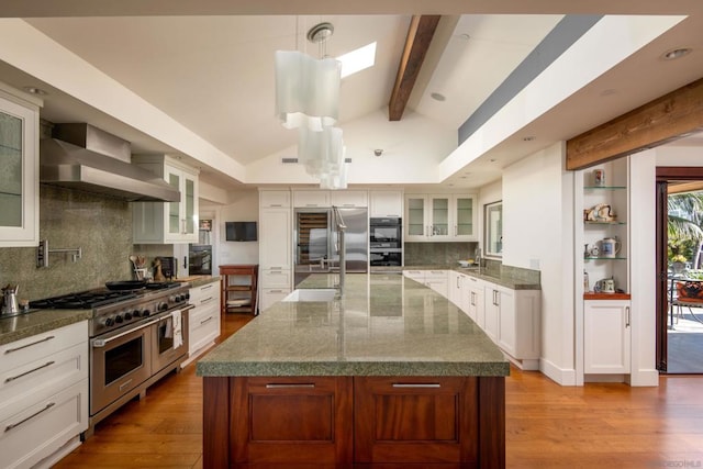 kitchen with appliances with stainless steel finishes, light hardwood / wood-style flooring, pendant lighting, and a center island with sink