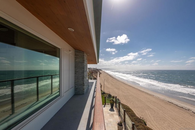 balcony with a water view and a view of the beach